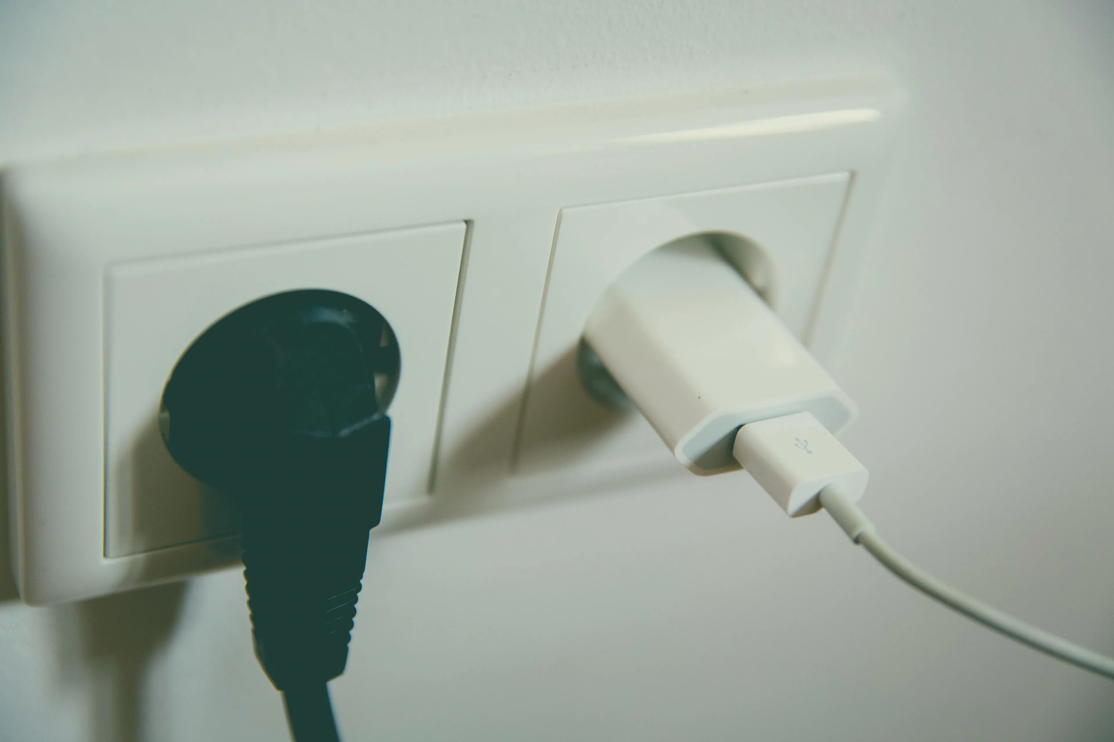 Phone charger plugged into wall socket with cable, illustrating energy transformation in general science knowledge quiz.