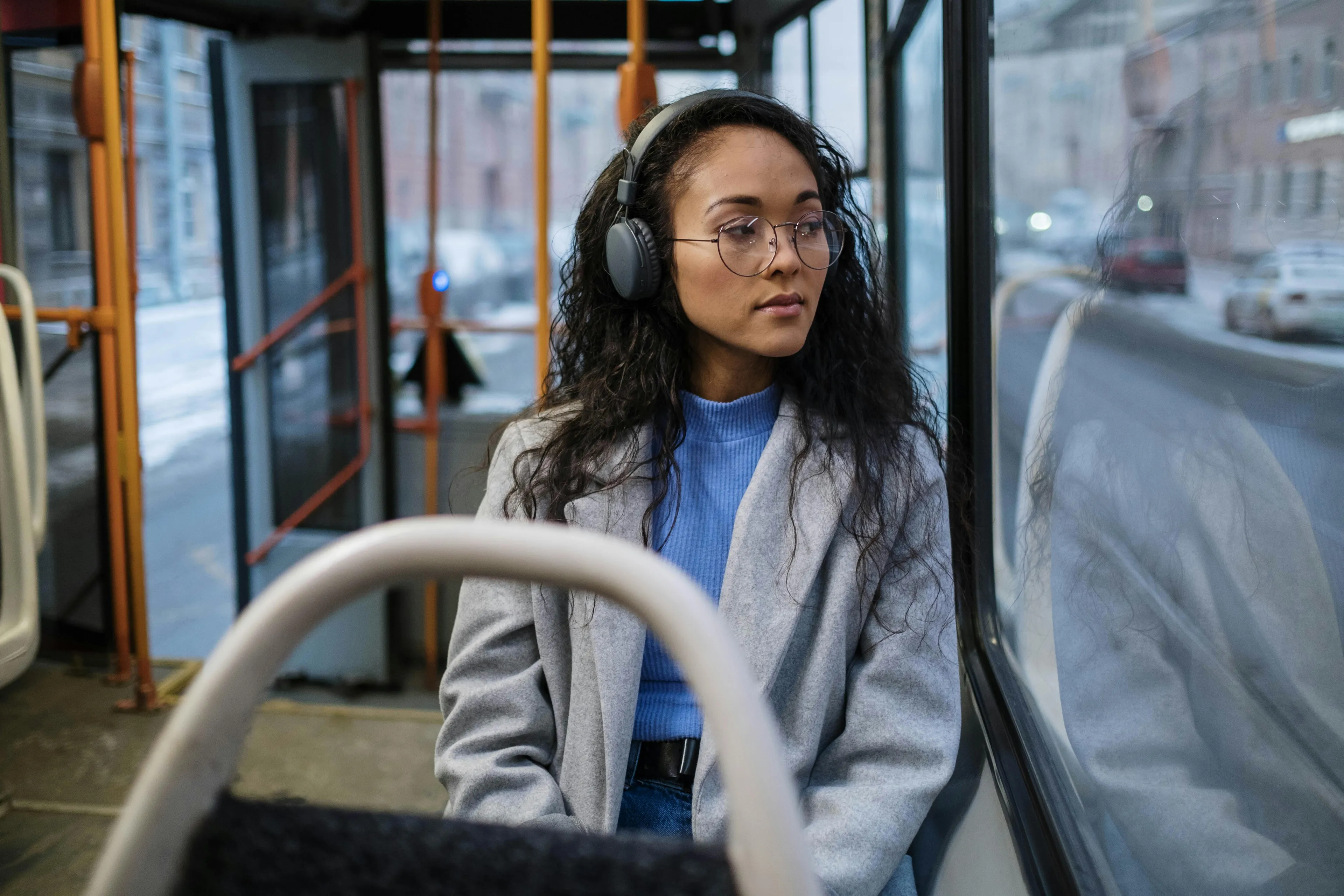 Passenger wearing headphones sitting on a bus, illustrating general science knowledge quiz about acceleration and motion.