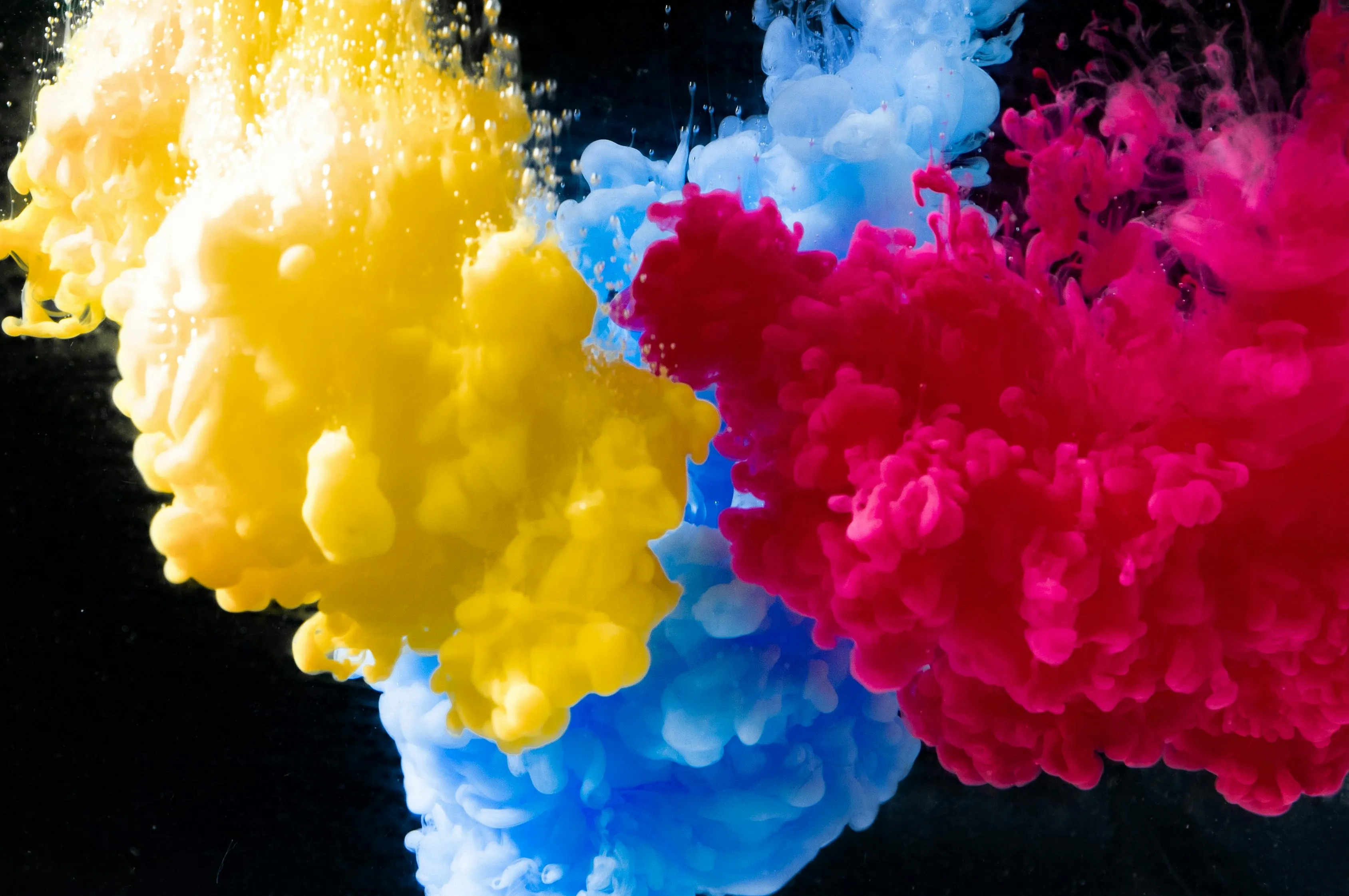 Yellow, cyan, and magenta pigments mixing underwater, illustrating general science knowledge quiz color theory concept.