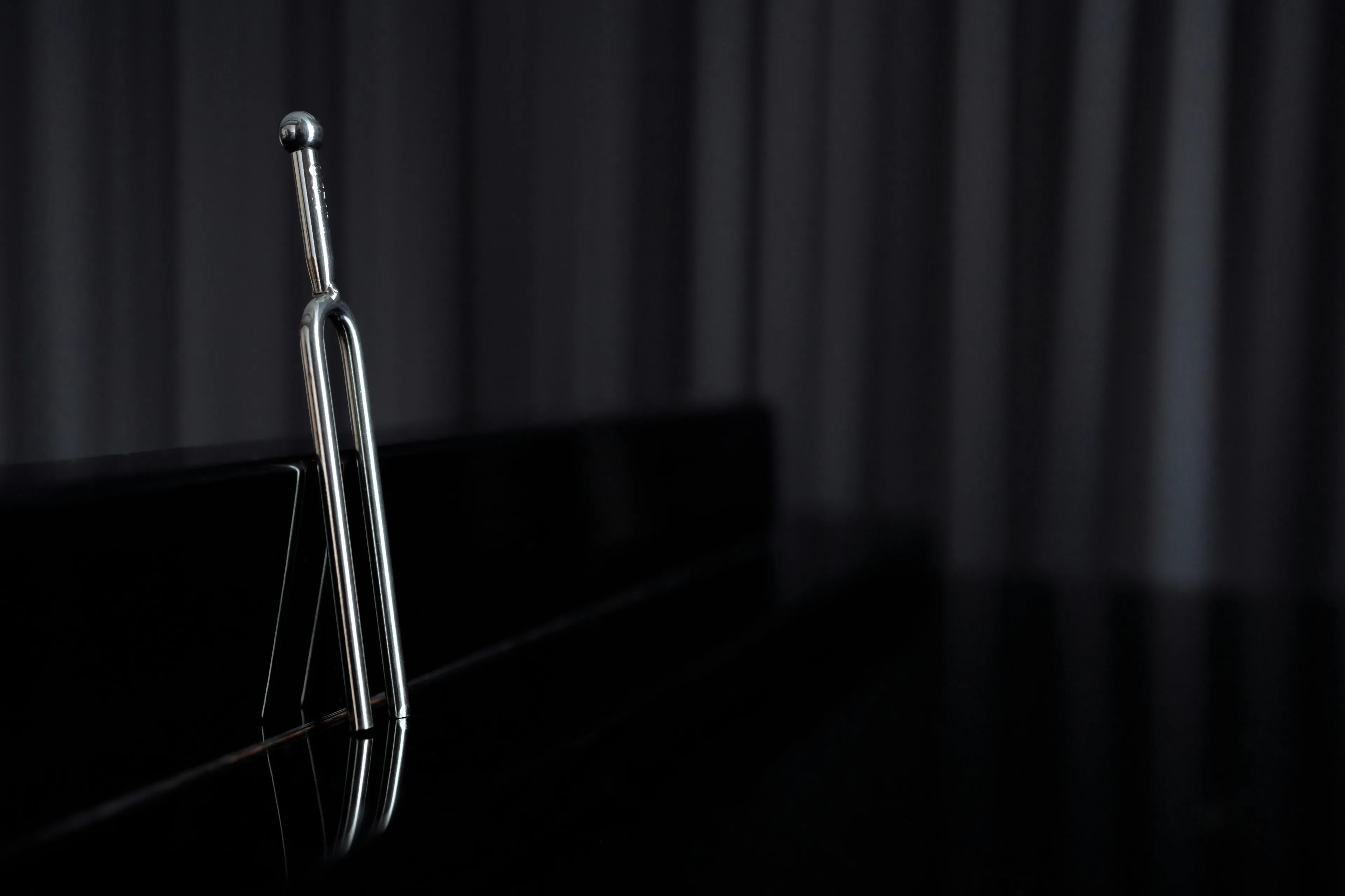 Tuning fork standing on black surface, illustrating sound energy conversion in general science knowledge quiz concept.
