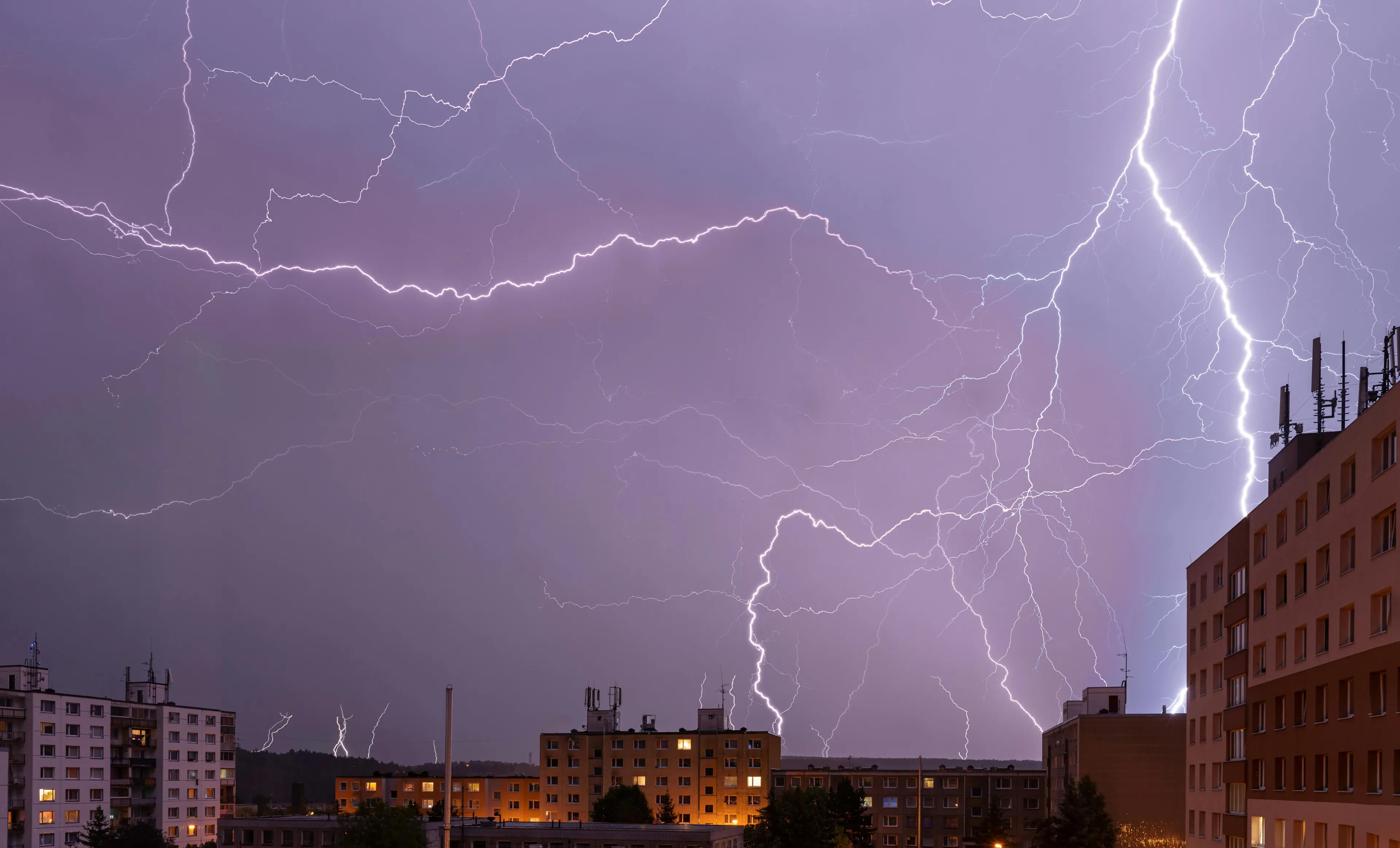Lightning strikes a large building during a thunderstorm, illustrating the delay caused by the speed difference of light and sound.