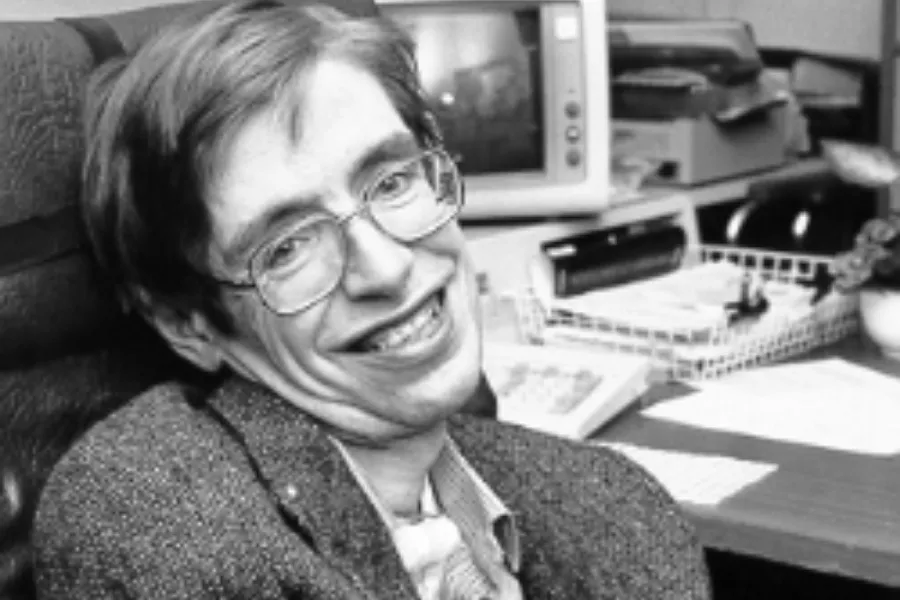 Stephen Hawking smiling in an office setting, known for his work related to the Big Bang theory and cosmology.