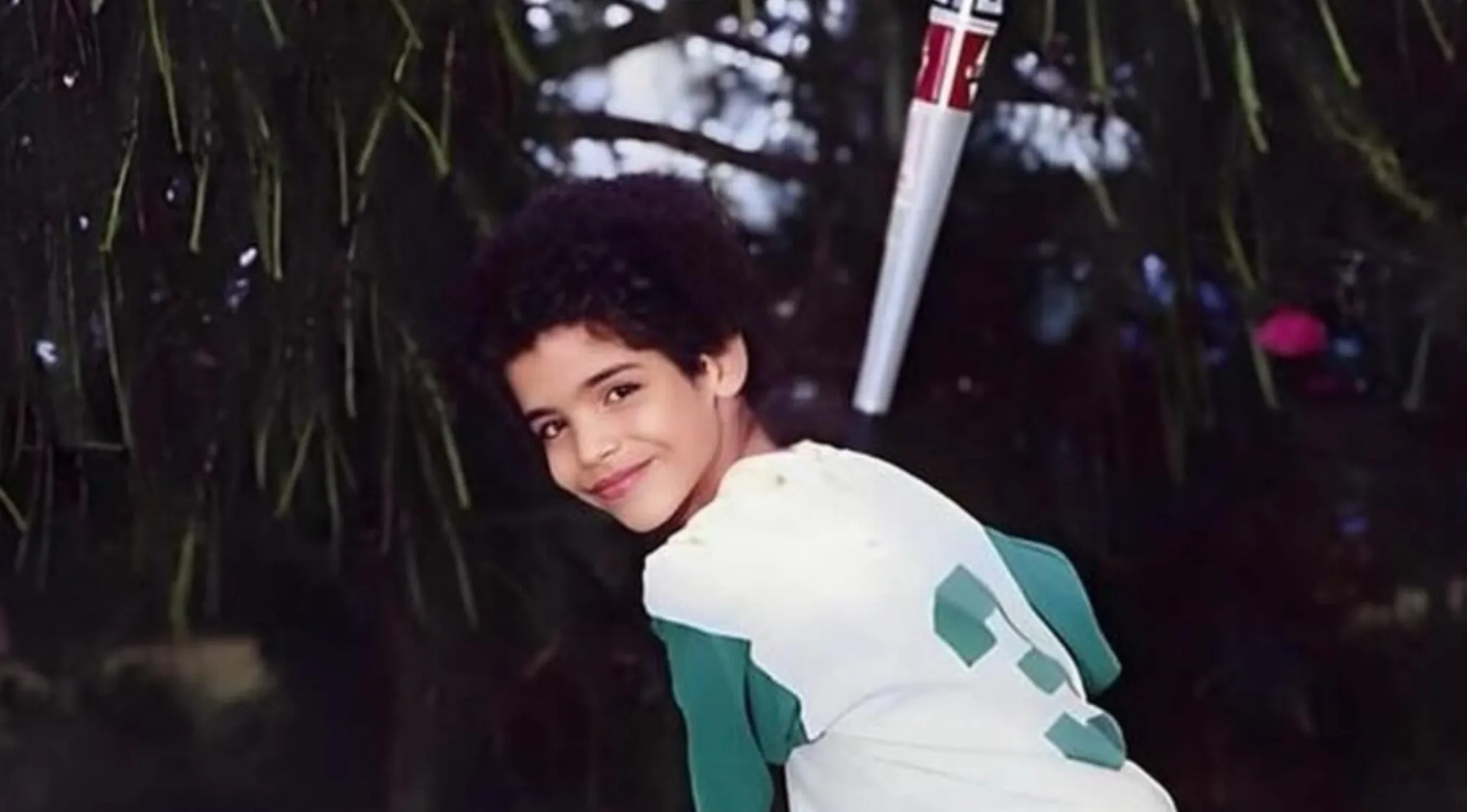Young boy smiling outdoors holding a baseball bat, capturing a moment in celebrities as kids photos.