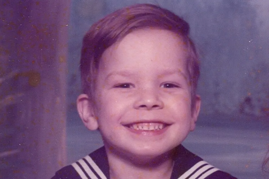 Young Jimmy Fallon smiling in a vintage sailor outfit, showcasing a childhood portrait with a blue background.