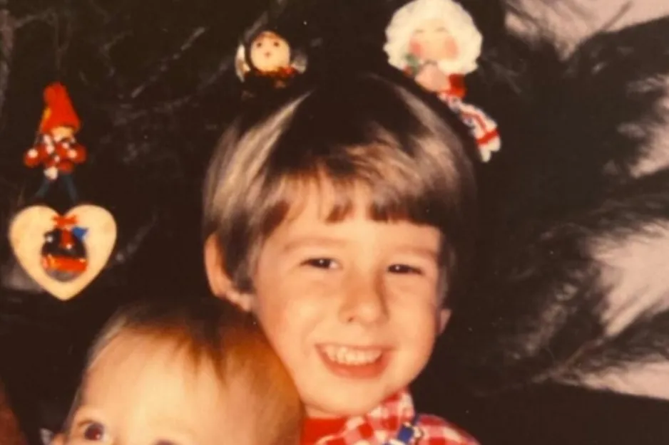 Young Jimmy Fallon as a child smiling in a vintage photo with Christmas decorations in the background