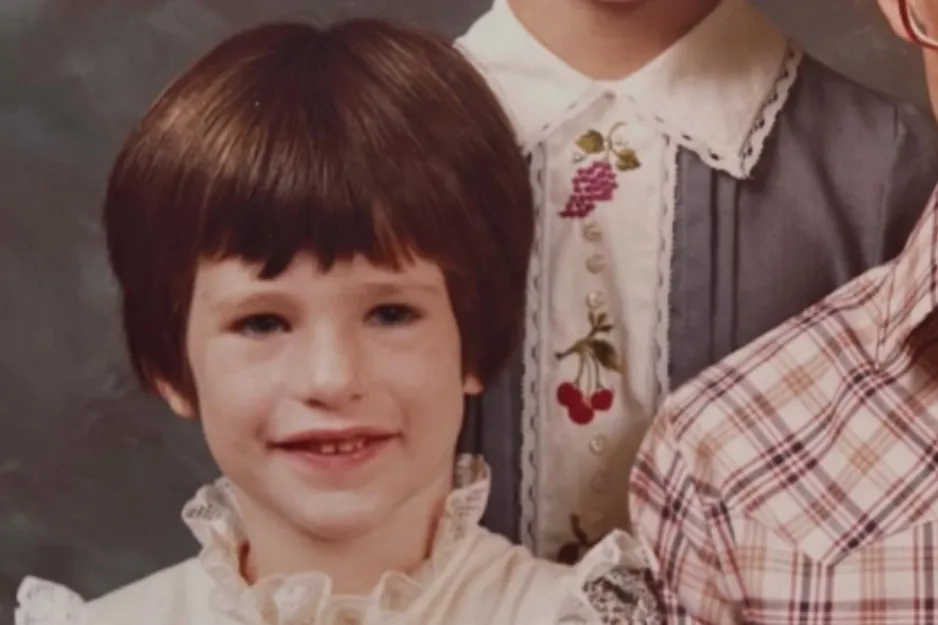 Young child with short brown hair wearing a white ruffled blouse in a vintage portrait asking which one is Adele