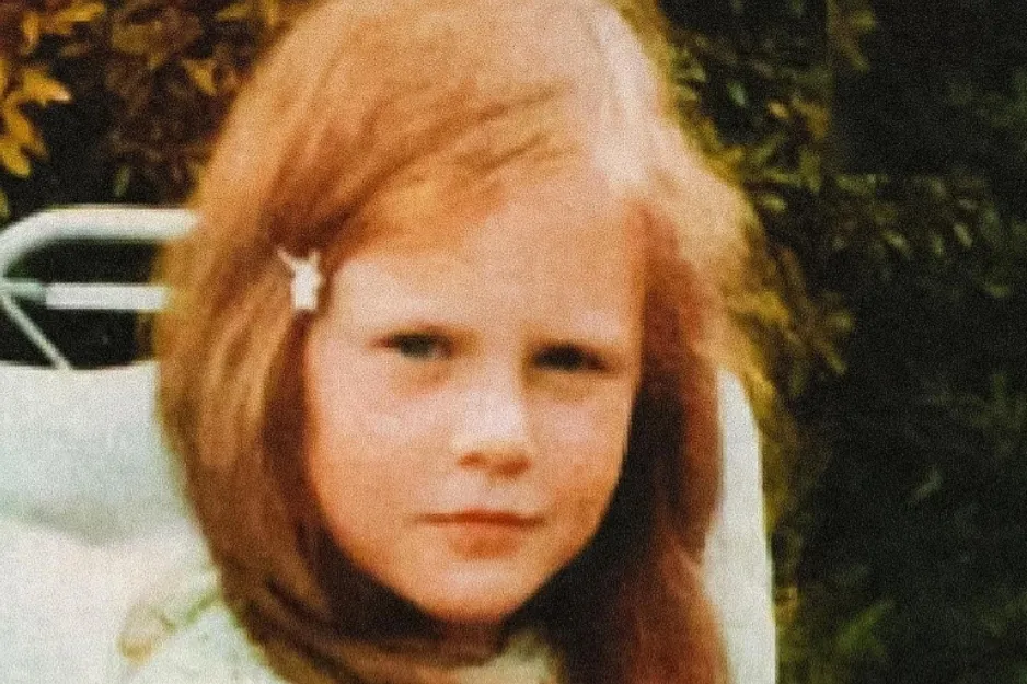 Young girl with red hair sitting outdoors surrounded by greenery, featuring Brie Larson as a child.