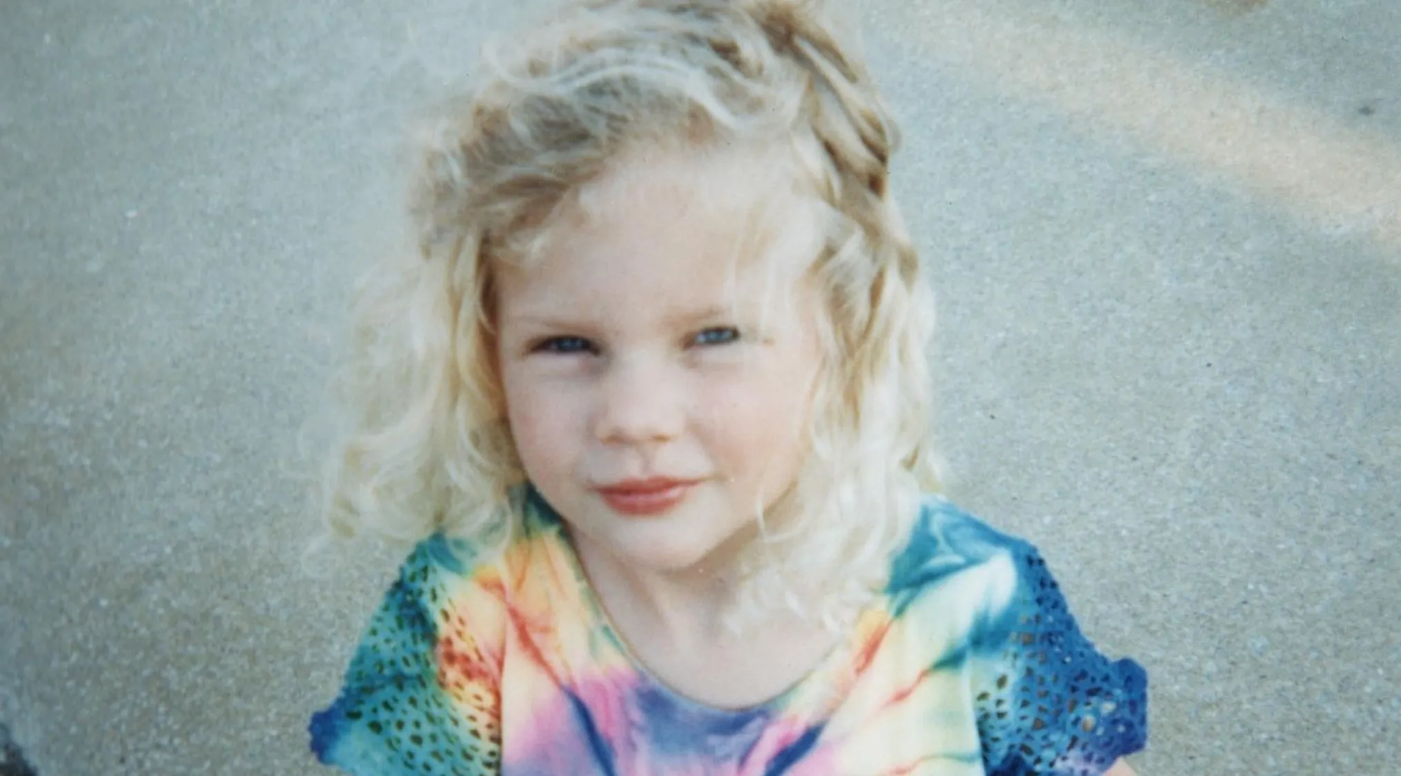 Blond curly-haired child in a colorful tie-dye shirt, posing outdoors for celebrities as kids photo series.