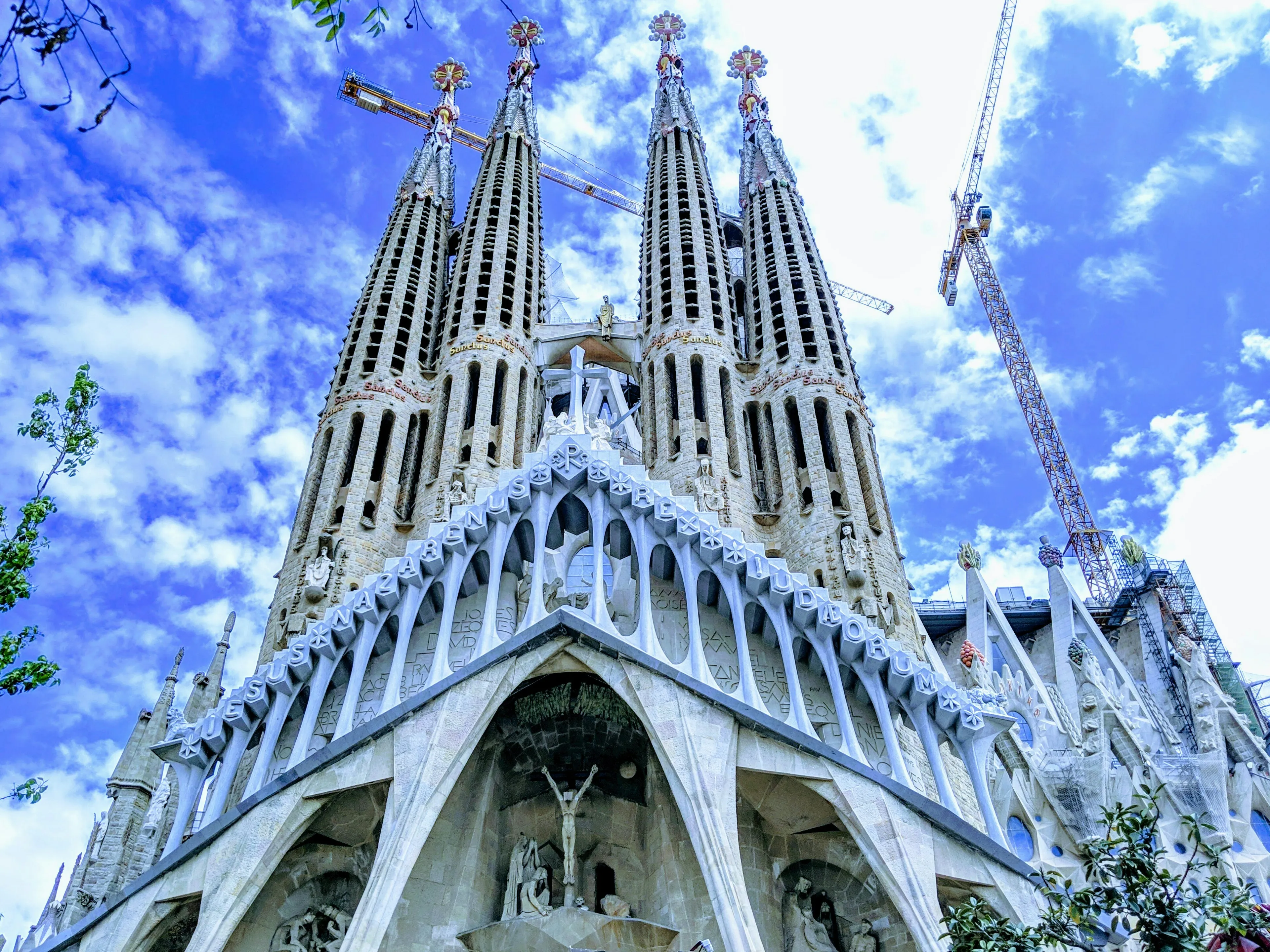 Sagrada Familia monument with tall spires and cranes under a blue sky, famous landmark in Barcelona city.