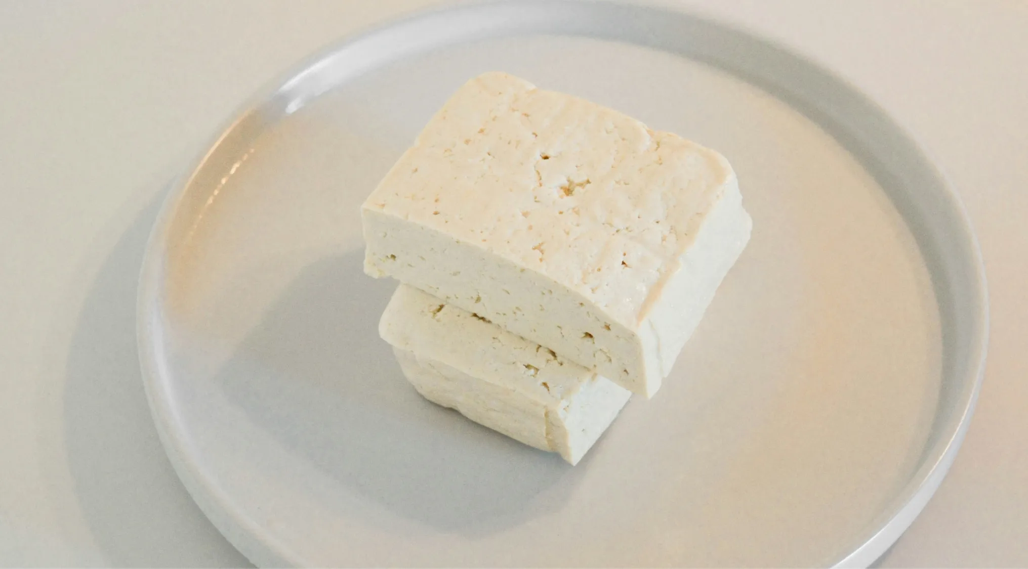 Two blocks of tofu on a white plate, illustrating the main ingredient in tofu for a general knowledge quiz.