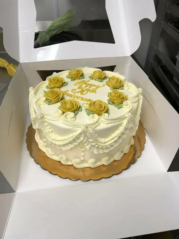 Elegant anniversary cake decorated with yellow roses and white icing in box