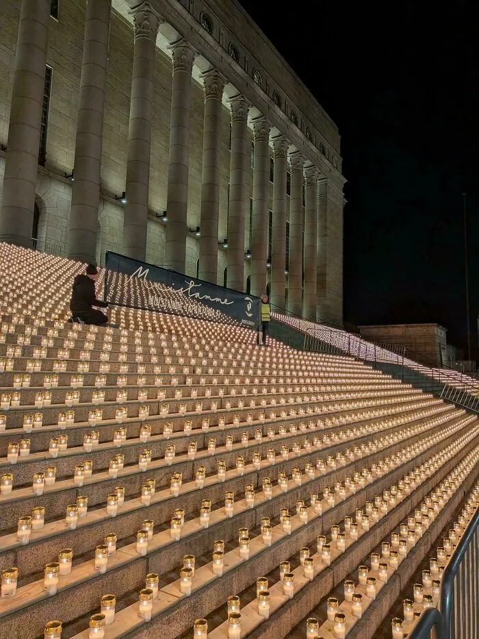 A grand building staircase adorned with hundreds of lit candles, illustrating a large-scale event related to consumerism.