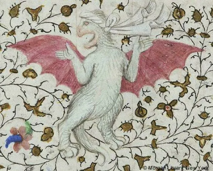 Medieval art depiction of a bizarre creature with red wings surrounded by floral and vine decorations.