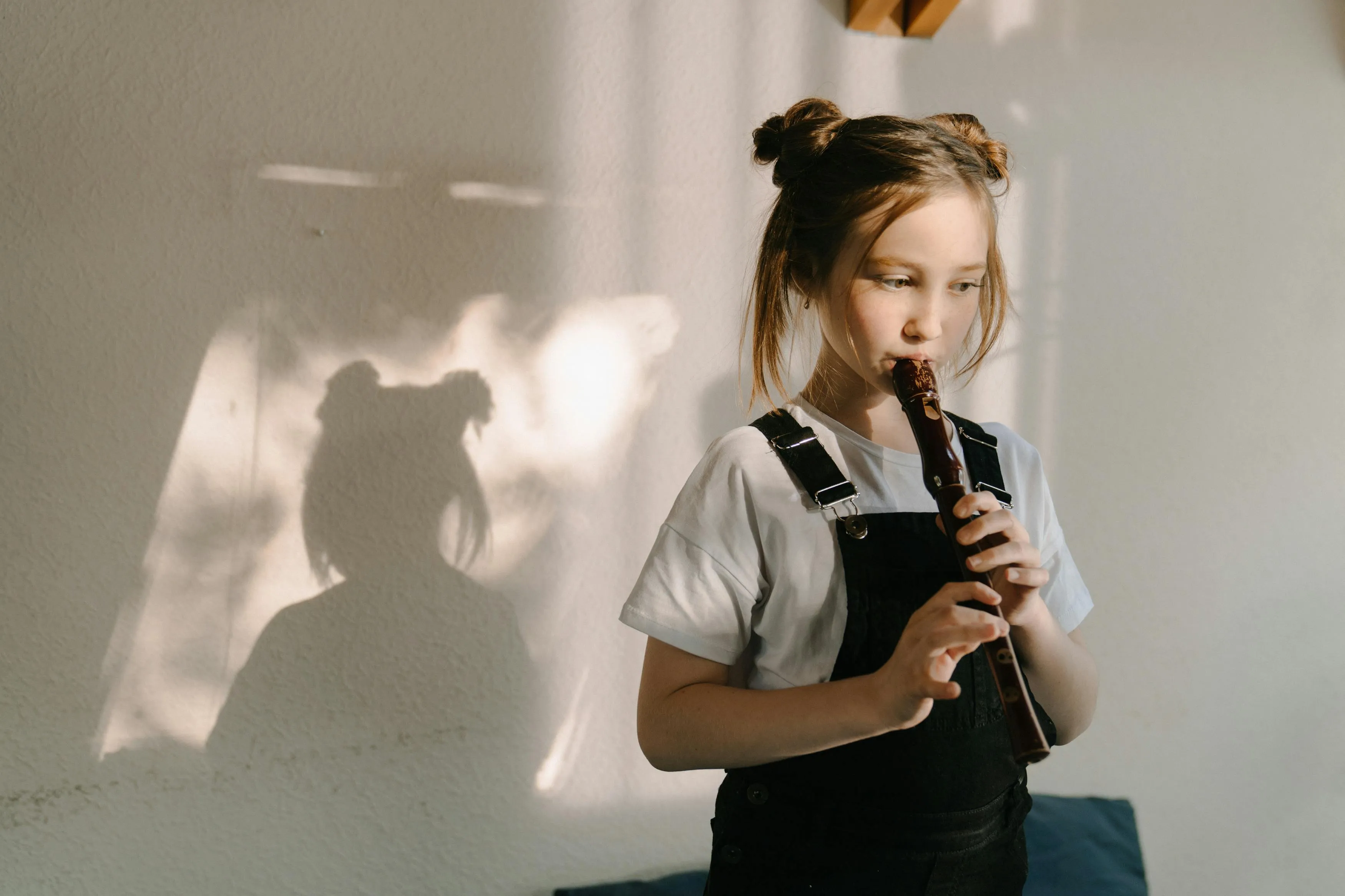 Young girl playing a recorder during a talent show, a classic kid birthday party activity in a bright room