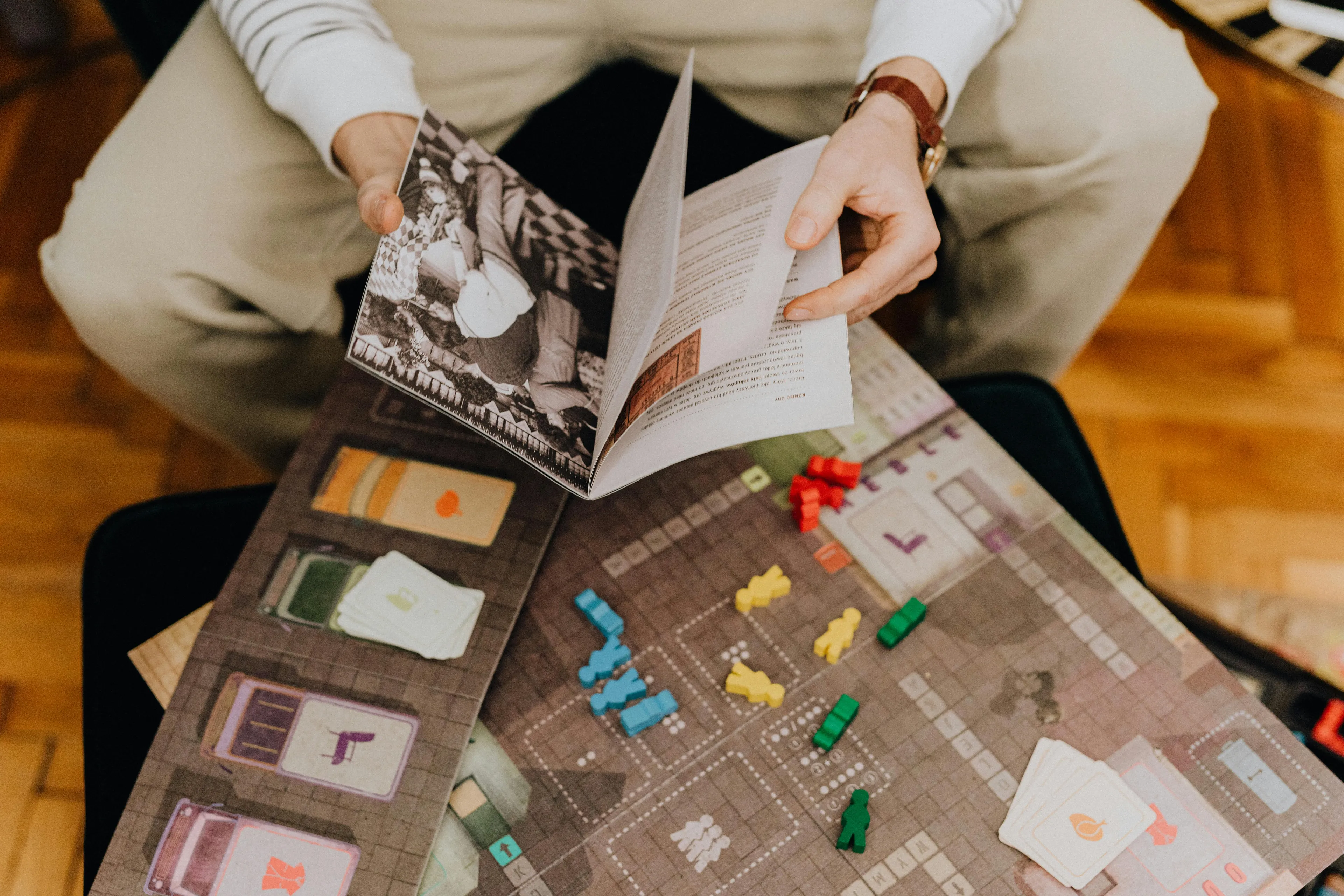 Person holding a game board booklet, preparing for a competitive game night to unlock your inner group role.