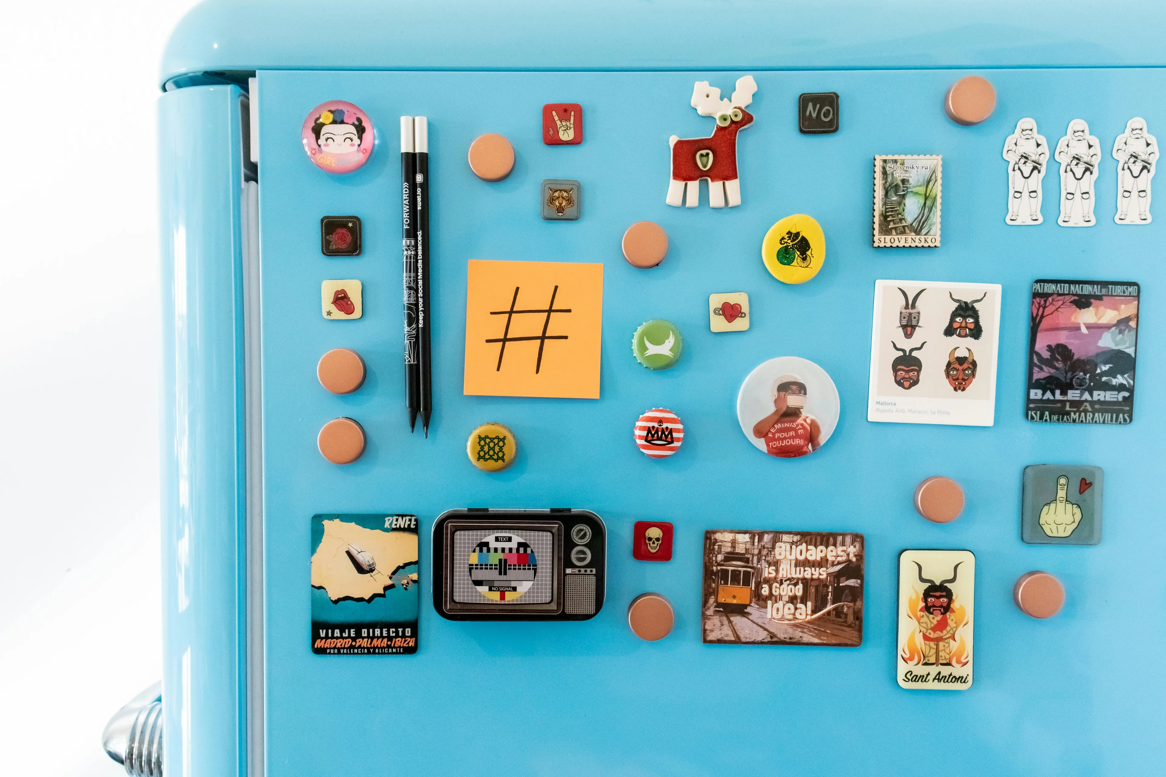 Blue fridge door covered with various colorful magnets, pins, and notes, illustrating group role expression.