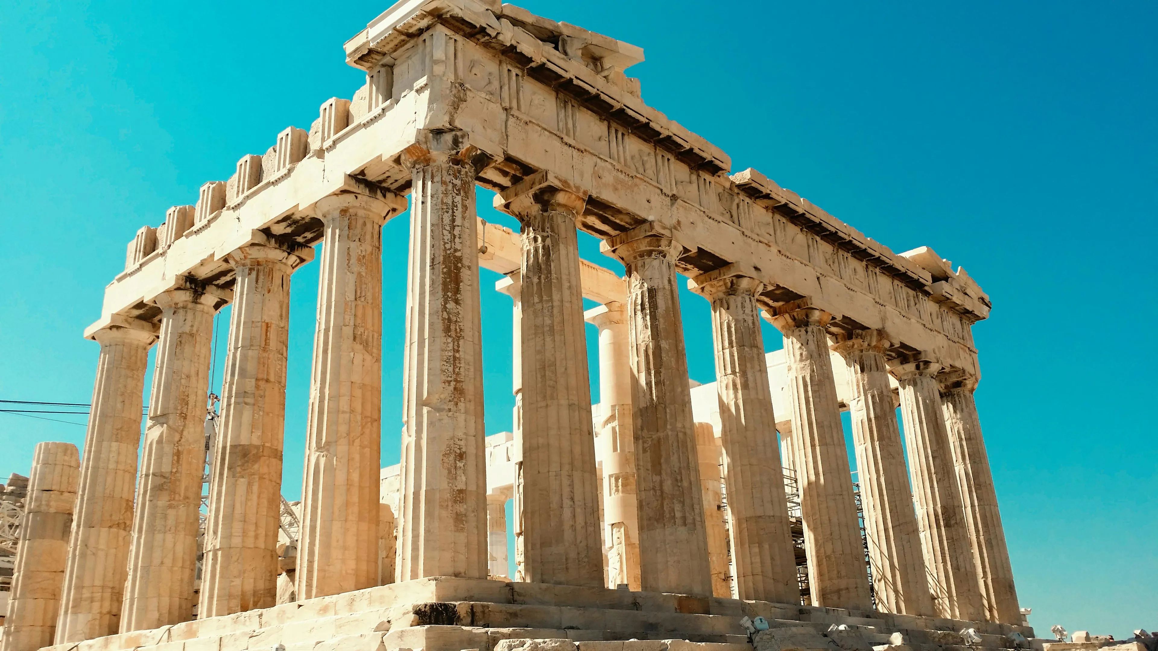Ancient Greek temple ruins under a clear sky representing the birthplace of democracy in modern Greece.