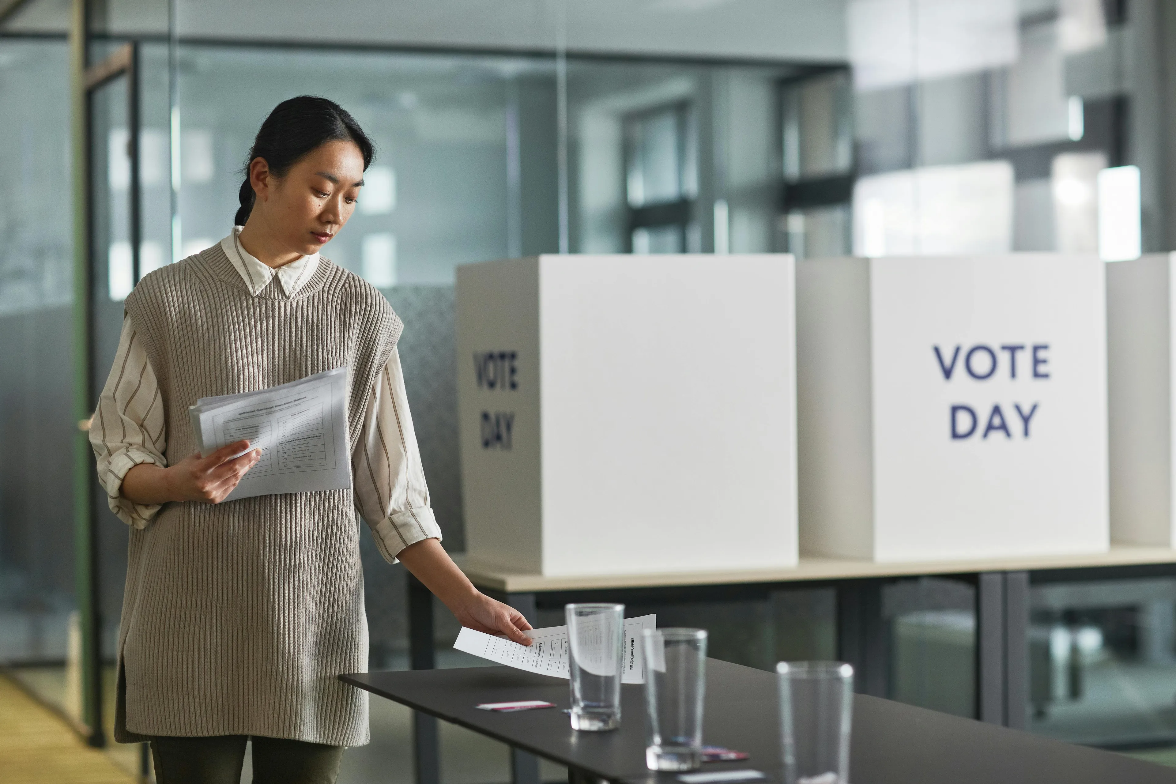 Woman casting a ballot in a voting booth on vote day representing countries that were first with voting rights.