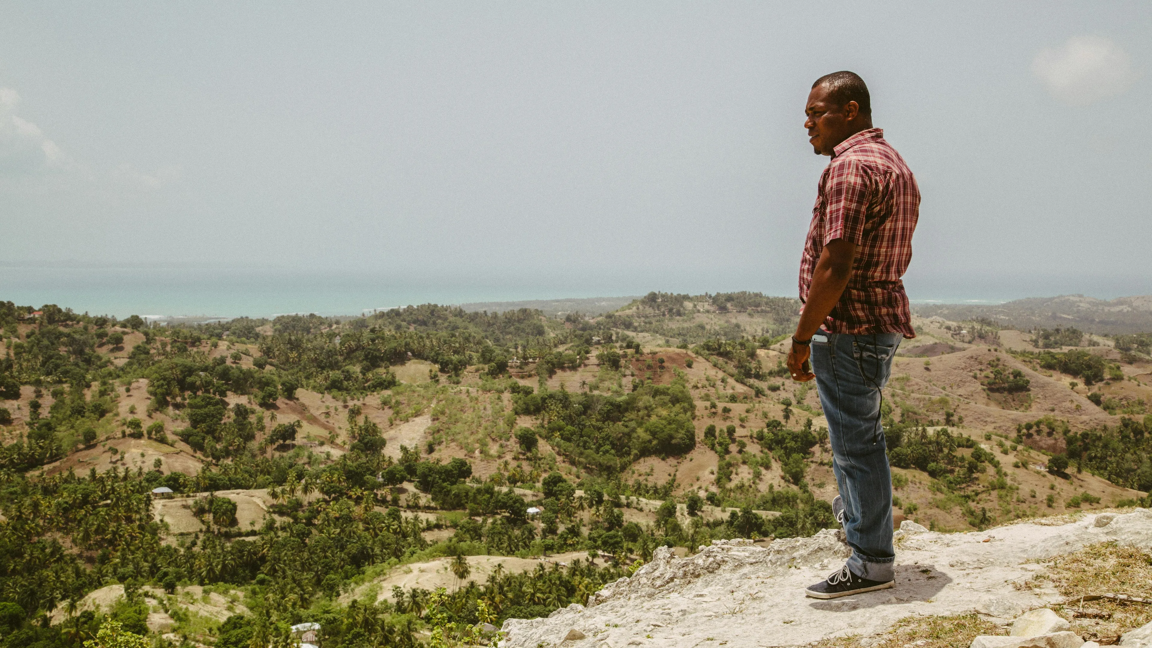 Man standing on a hill overlooking a Caribbean landscape representing countries that were first in abolishing slavery.