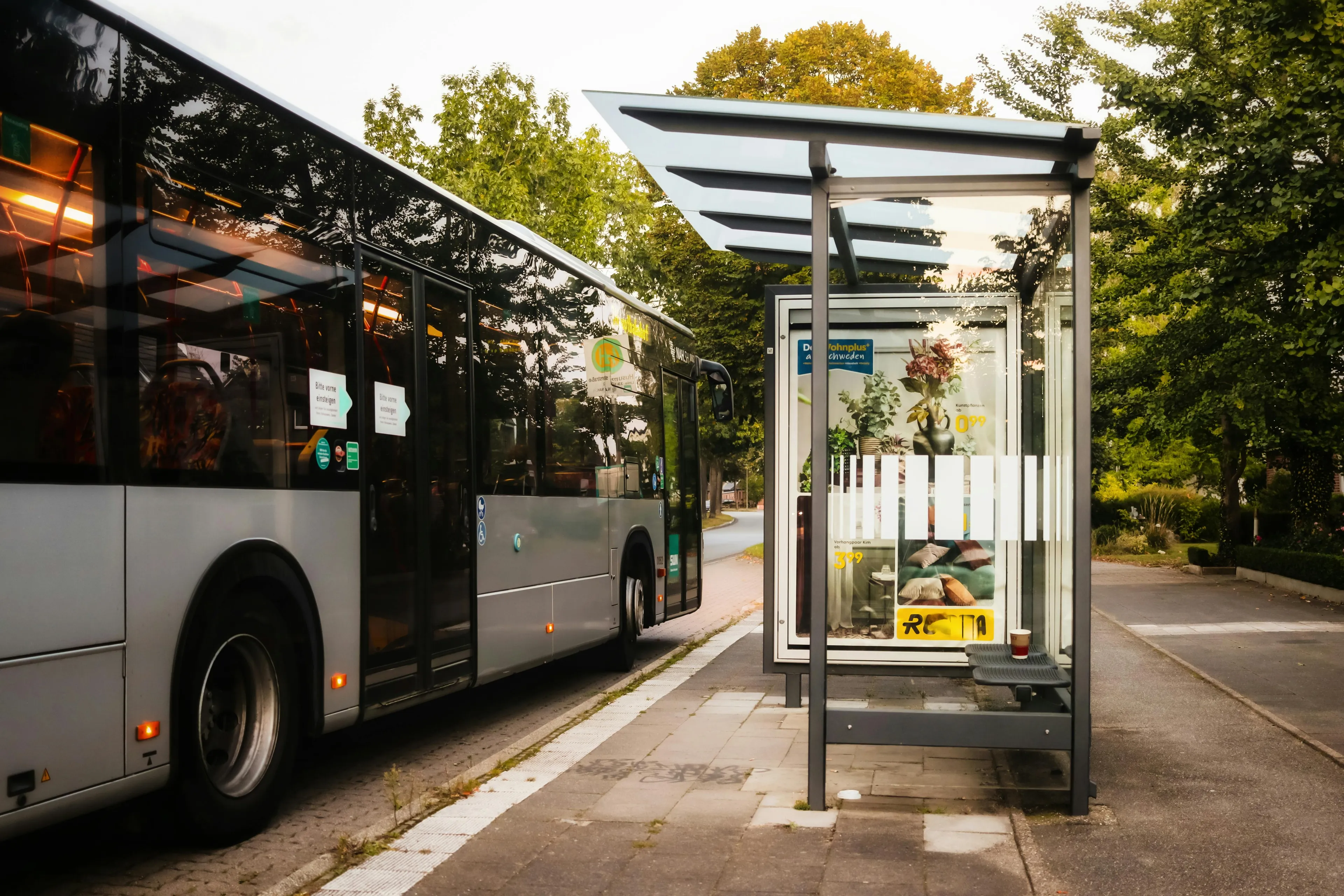 Bus at a modern bus stop surrounded by trees, illustrating public transport in a small country setting.