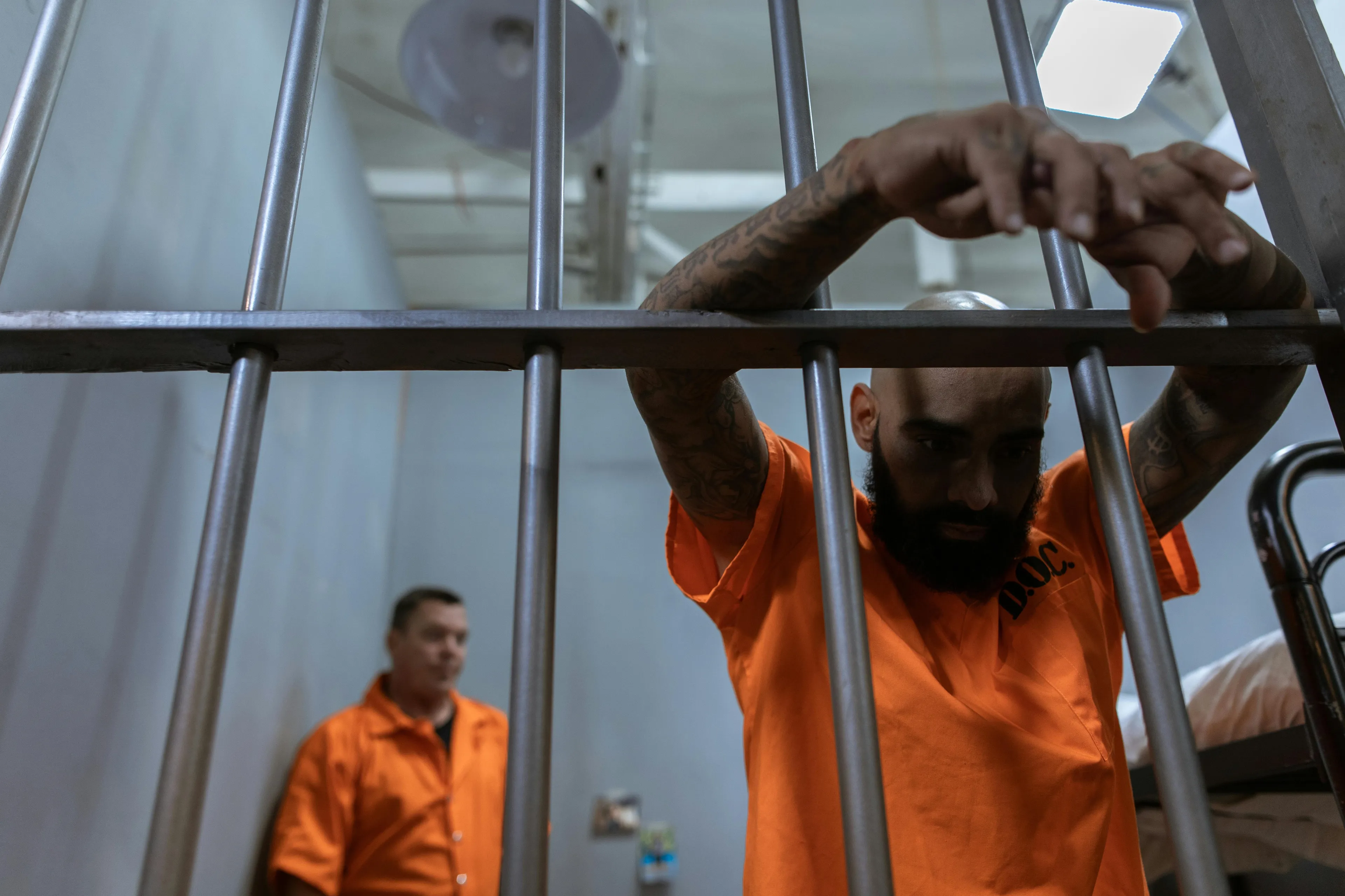 Two prisoners in orange uniforms behind jail bars, symbolizing capital punishment and countries that abolished it.