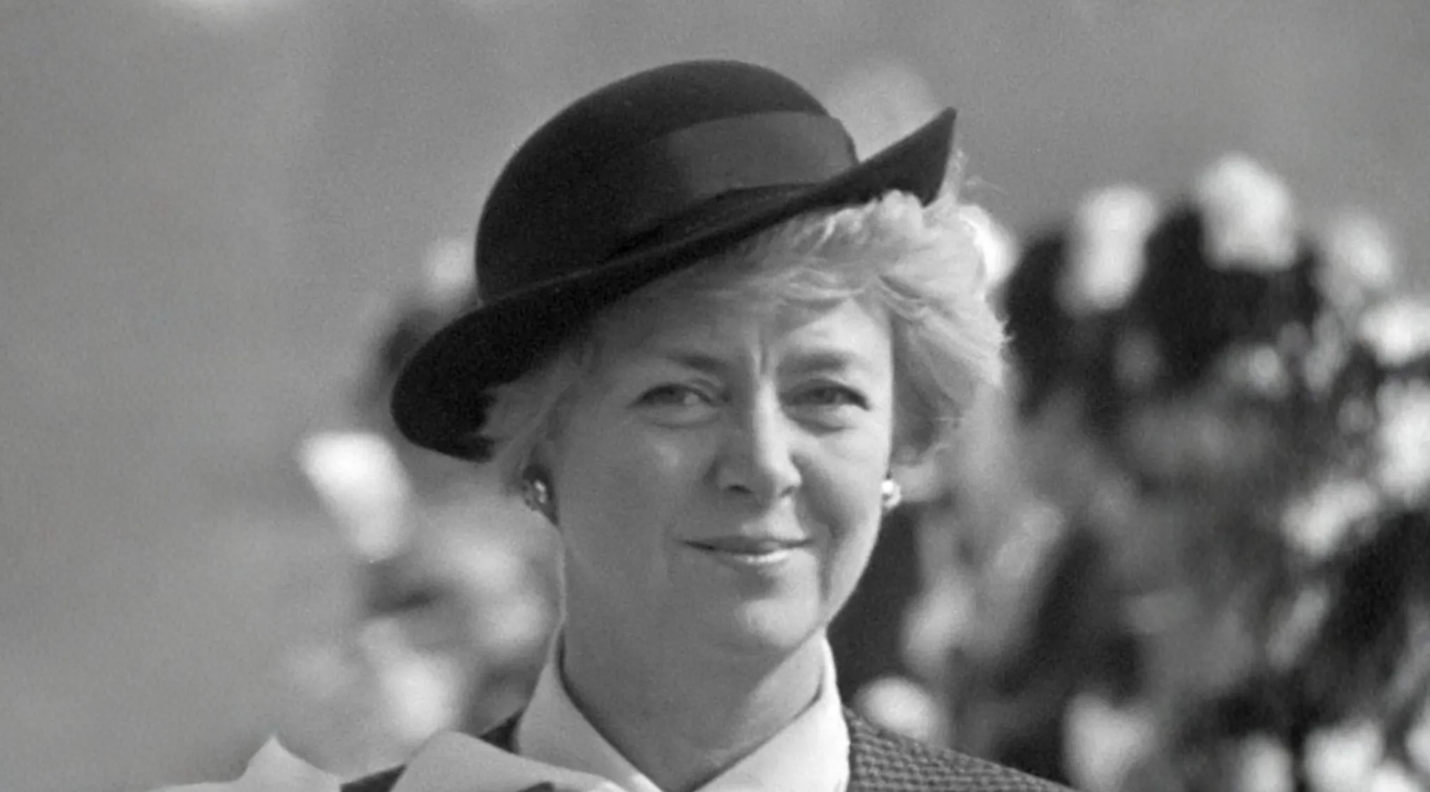 Black and white photo of a smiling woman wearing a hat, representing a country that first elected a female president.