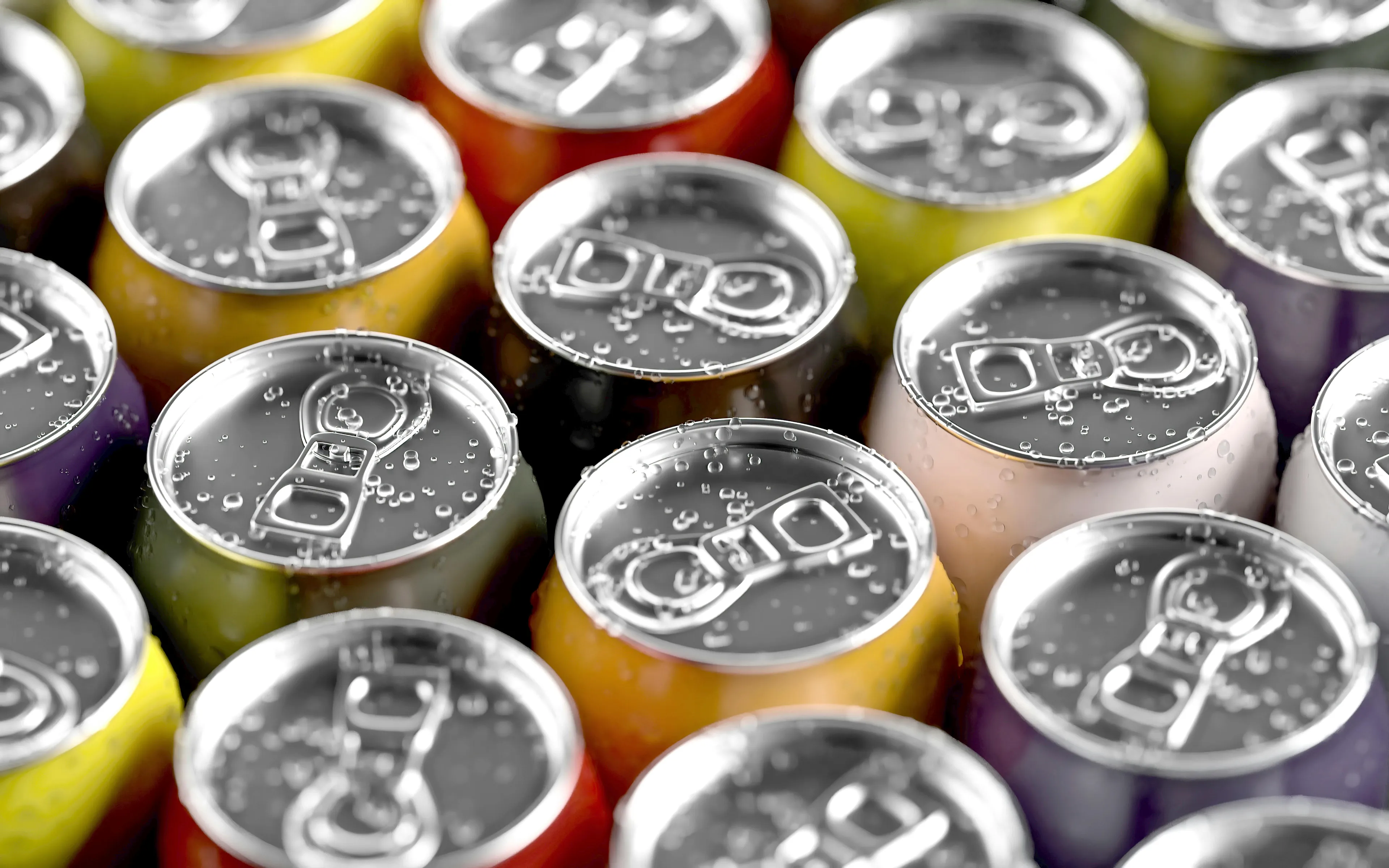 Close-up of colorful canned sugar-sweetened beverages with water droplets, highlighting countries first to tax sugary drinks.