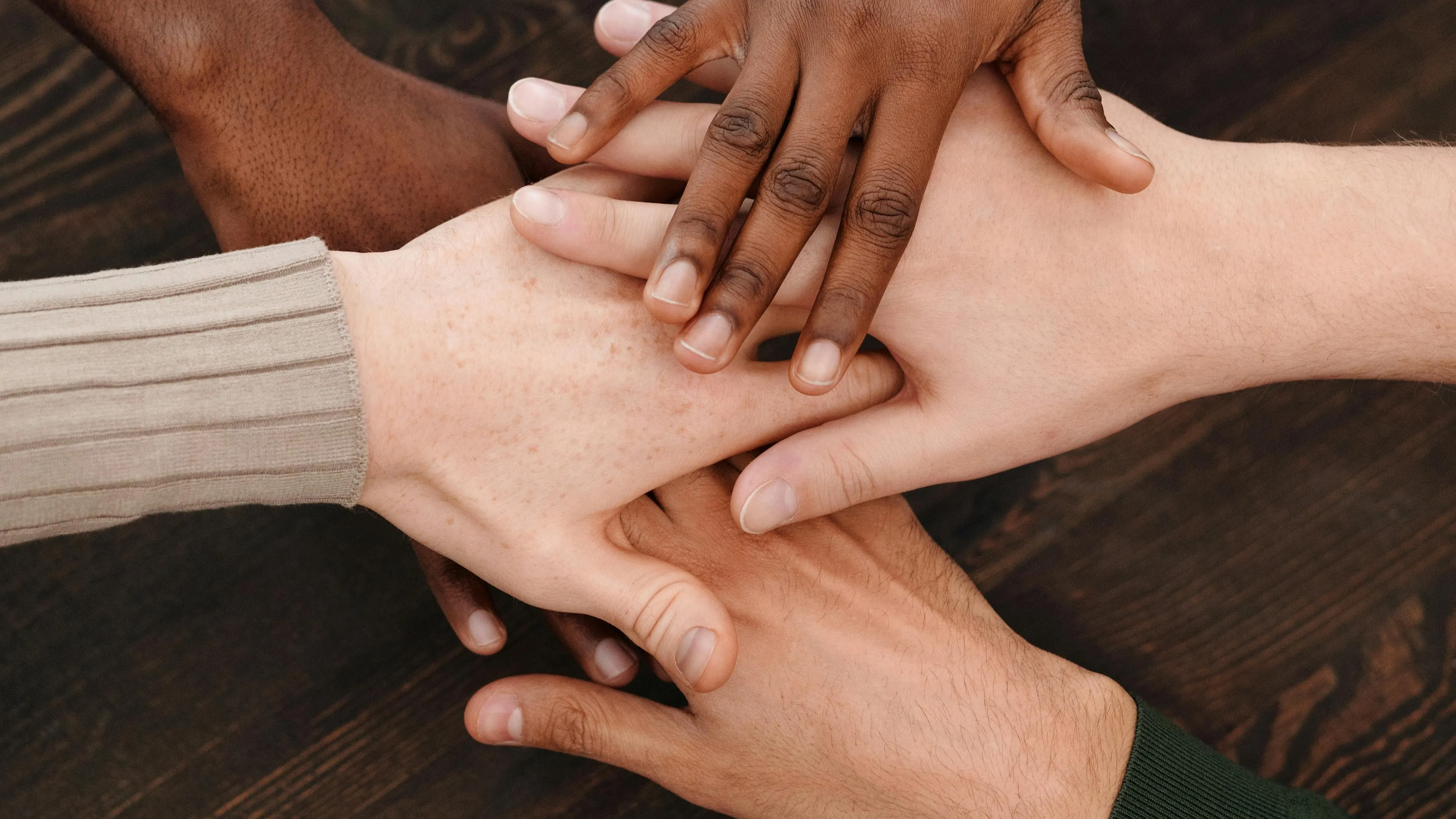 Diverse hands stacked together representing unity and official multiculturalism policy in countries.