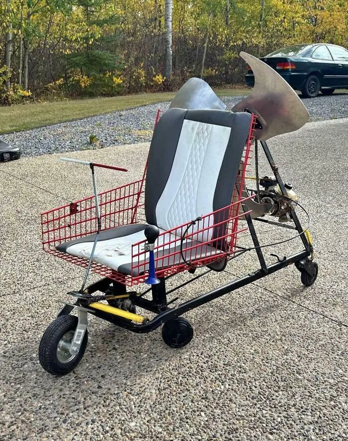 Homemade redneck engineering scooter with a car seat, metal basket frame, and a large fan blade in the back.