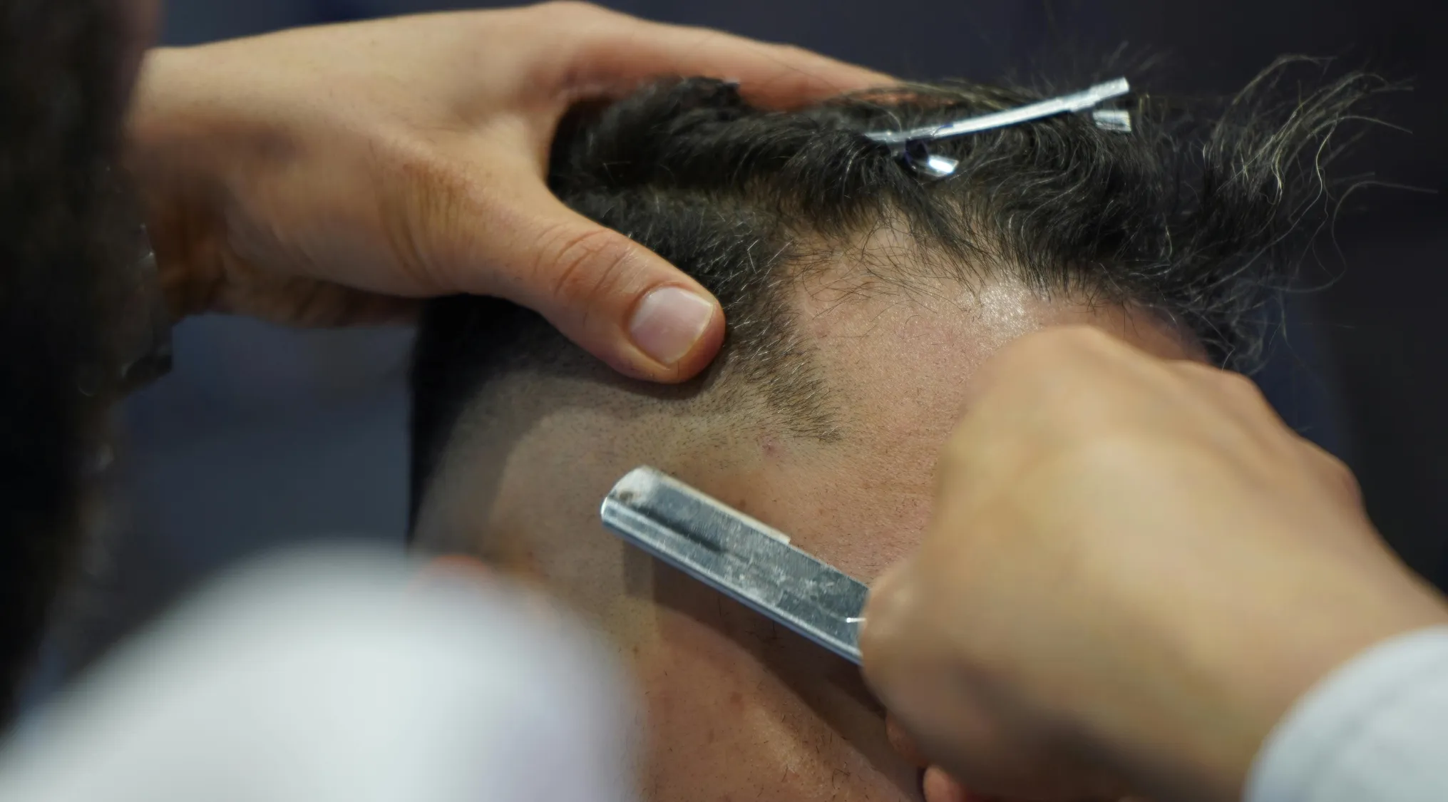 Close-up of a barber shaving a client’s hairline with a razor focusing on two truths and a lie concept.