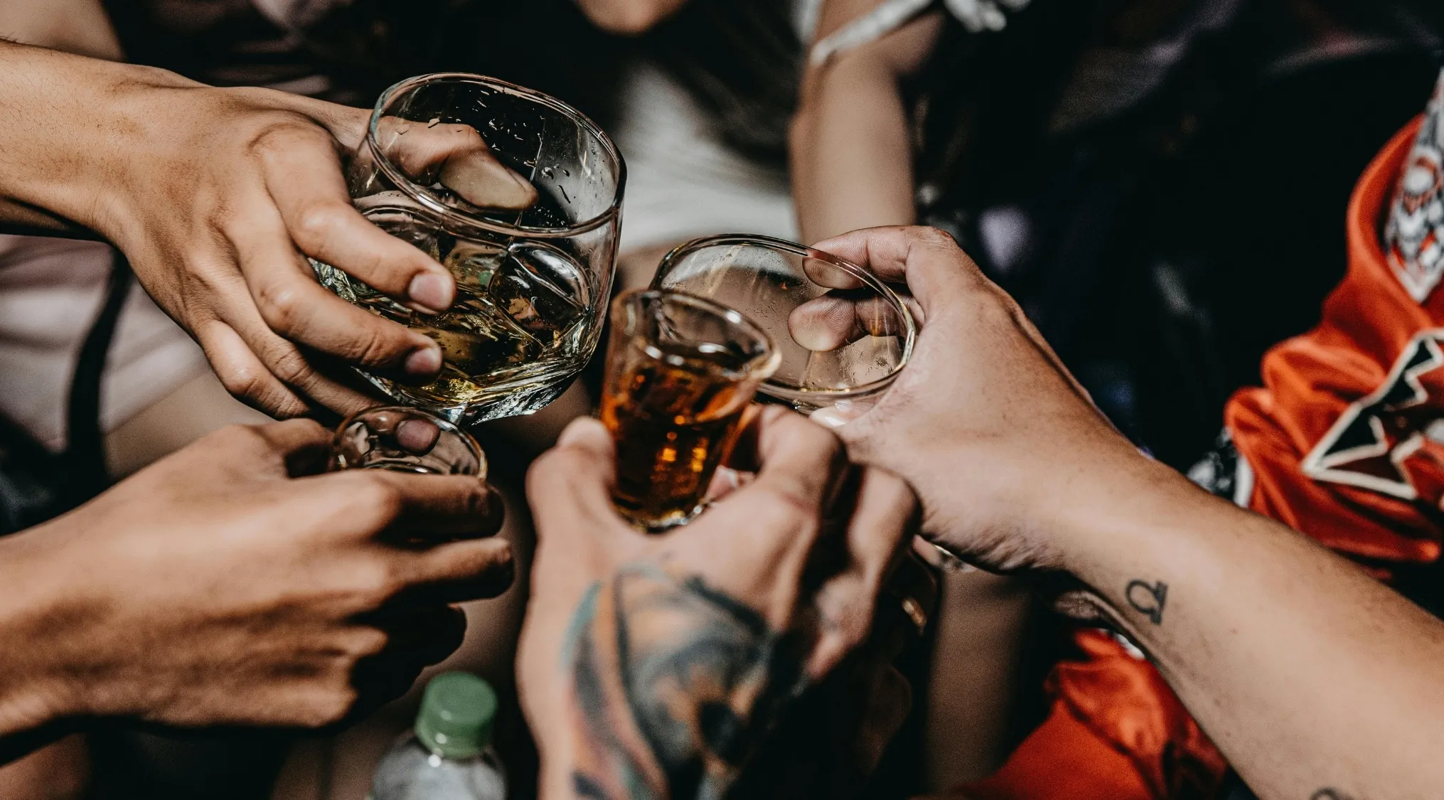 Group of people clinking glasses in a casual setting, playing two truths and a lie game with drinks.