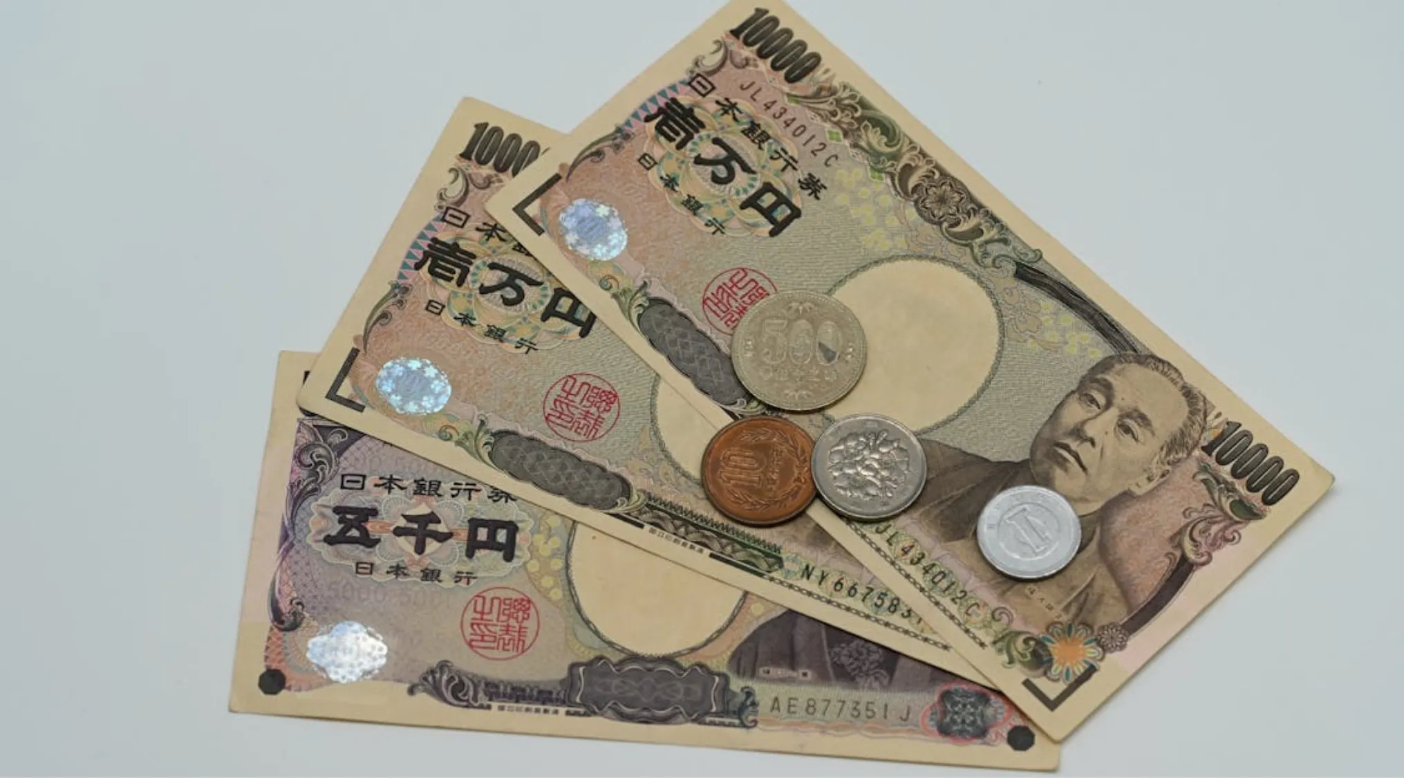 Japanese yen banknotes and coins arranged on a light surface representing currency used in Japan.