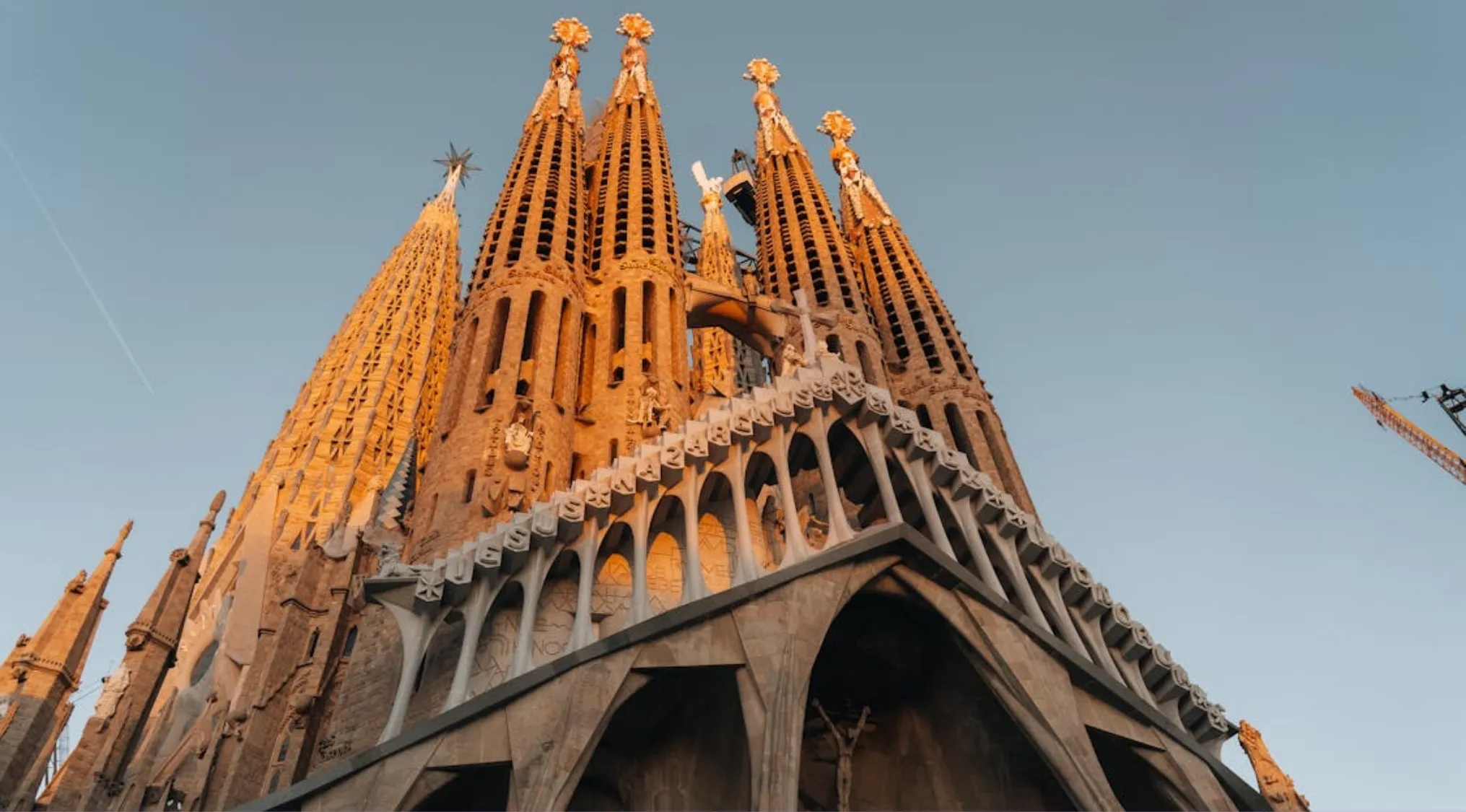 Sagrada Família cathedral in Barcelona during sunset with detailed Gothic architecture and clear sky background.