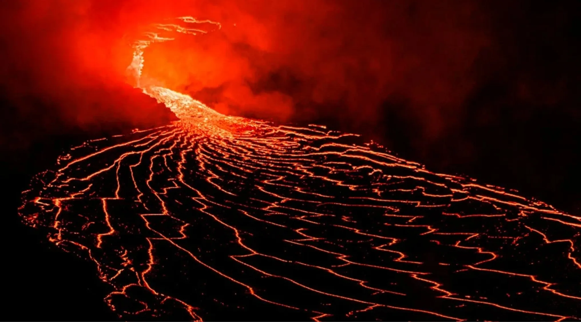Lava flow from volcanic eruption glowing bright orange against dark background, symbolizing Mount Vesuvius eruption.