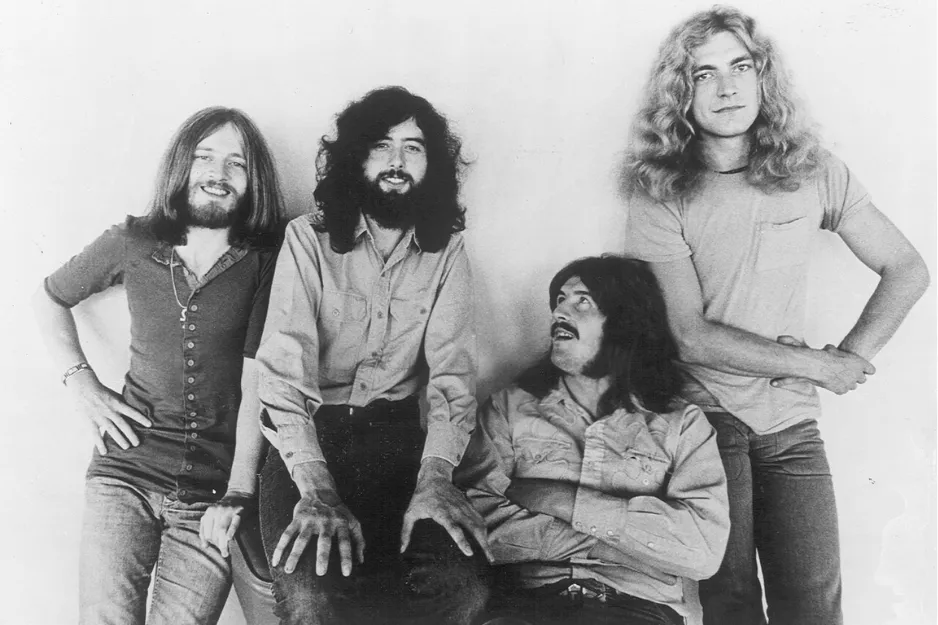 Black and white photo of Led Zeppelin band members posing together in casual 1970s clothing and hairstyles.