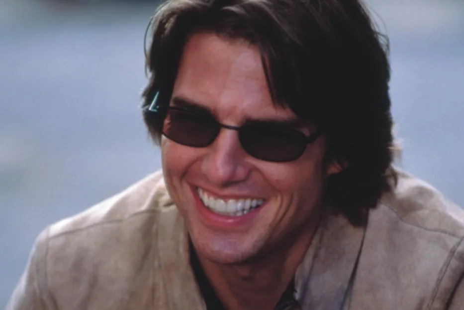Tom Cruise smiling wearing sunglasses and a beige jacket in an outdoor setting related to James Bond actors.