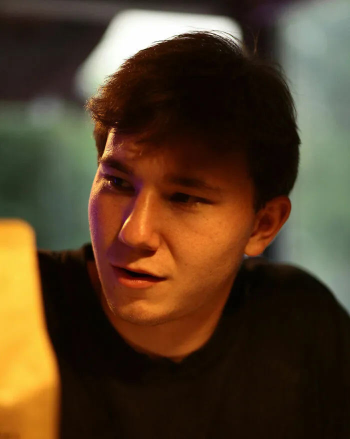 Young man indoors looking curious and puzzled, reflecting on weird and unhinged family traditions he probably doesn't have.