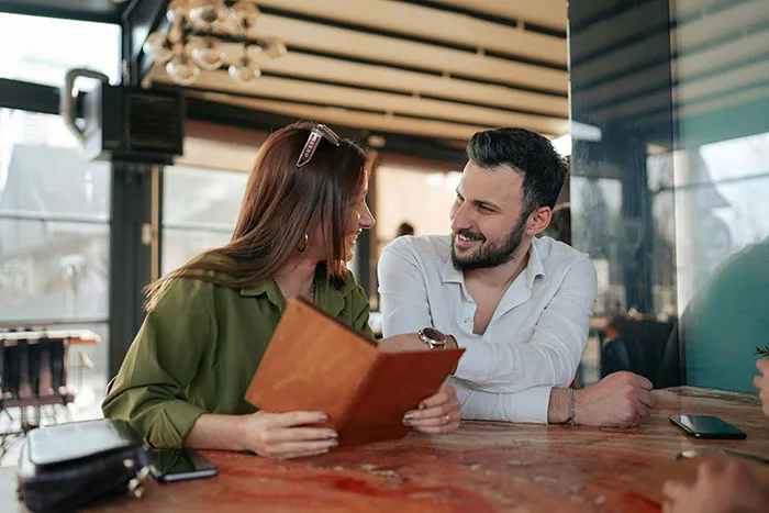 A man and woman smiling and talking at a cafe, illustrating things men keep to themselves but want to tell women.