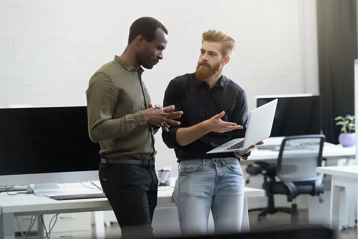 Two men in an office having a serious discussion, illustrating moments people regretted opening their mouths.
