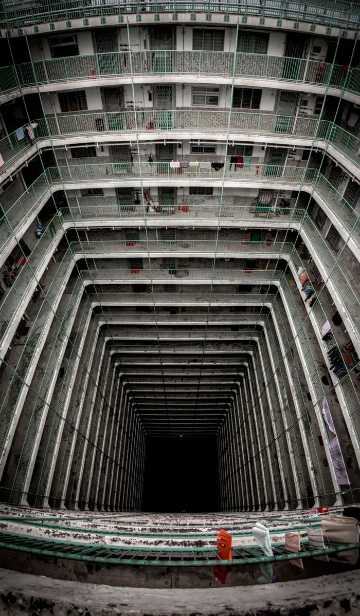 Dystopian urban hell interior of a high-rise building with many floors and a dark central void showing urban density.