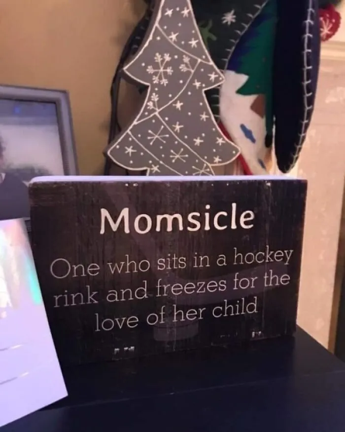 Wooden sign reading Momsicle, describing a mom freezing at a hockey rink, related to Canada memes and poutine cravings.