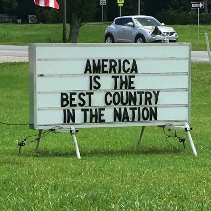 Humorous outdoor sign with incorrect phrasing showcasing uncultured and ignorant Americans in a public green space.