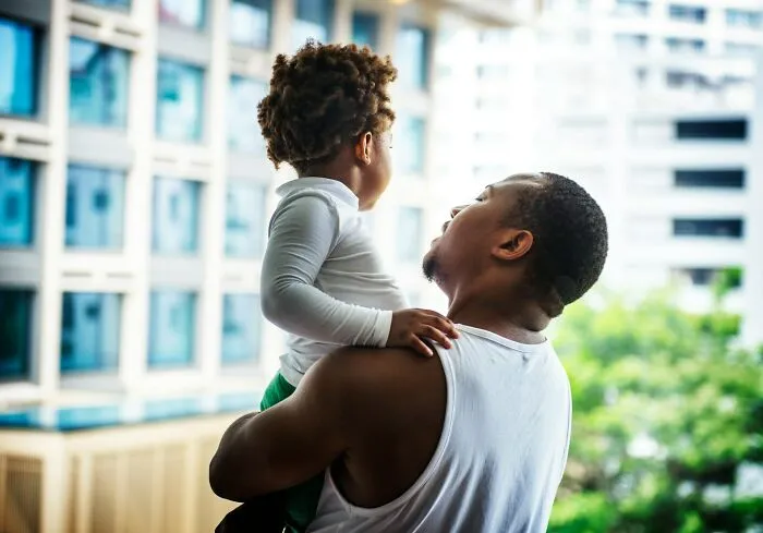 Man holding child outdoors in an urban setting, illustrating interactions between amazing women and men’s creepy advances.
