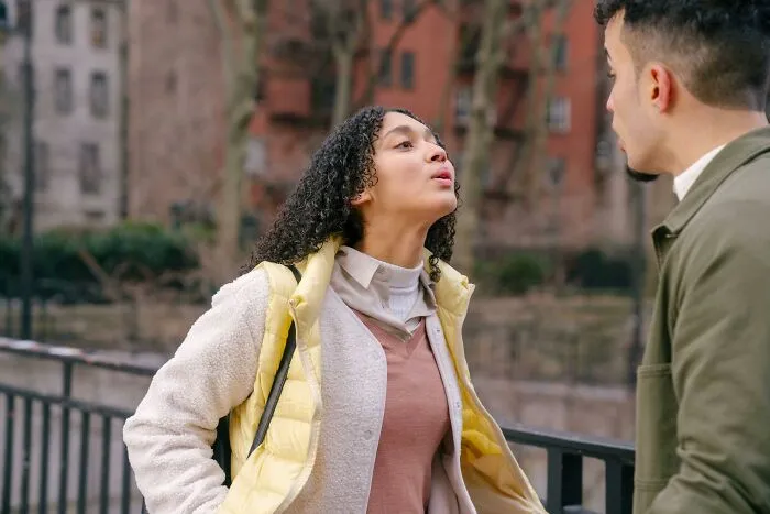 Woman in yellow jacket arguing with man outdoors near railing, illustrating a quick shortcut to personal hell concept.
