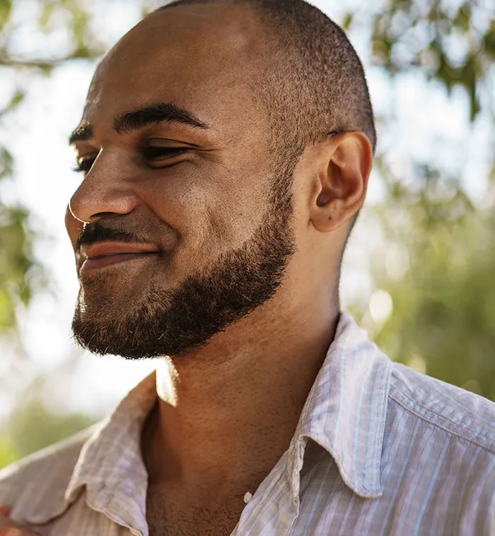Man with a beard smiling outdoors, representing first dates so horrible they should count as character-building trauma.