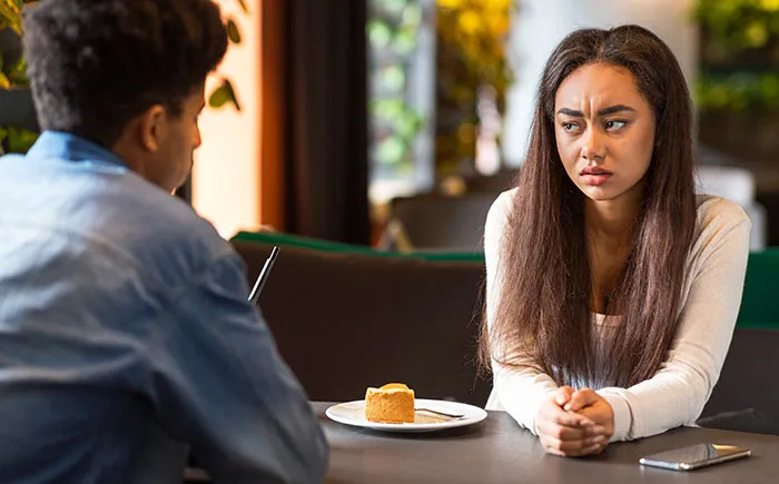 Young couple on a first date looking uncomfortable and upset, highlighting first dates so horrible they feel like trauma.