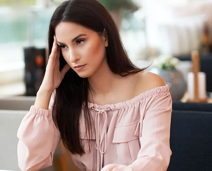 Young woman with long dark hair, looking frustrated during a first date experience in a modern cafe setting.
