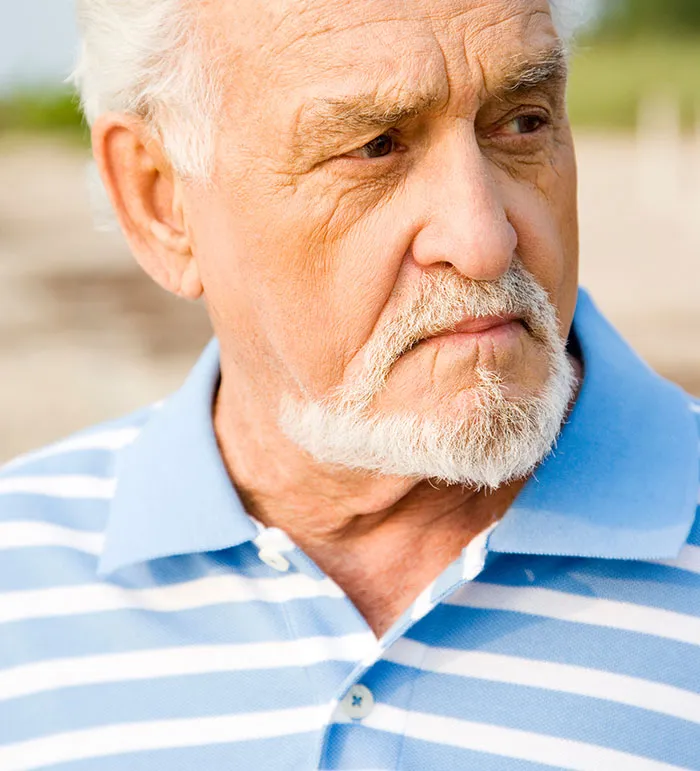 Elderly man with white beard and striped shirt looking pensively, reflecting on eerie and unexplained experiences.