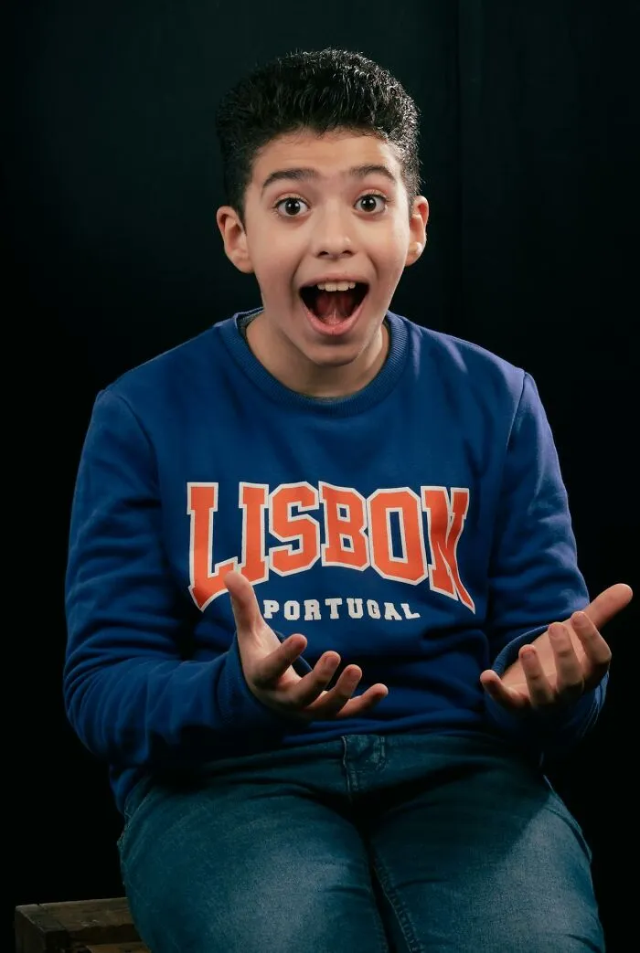 Boy in a blue Lisbon Portugal sweatshirt showing a surprised expression, representing true stories that sound bizarre.