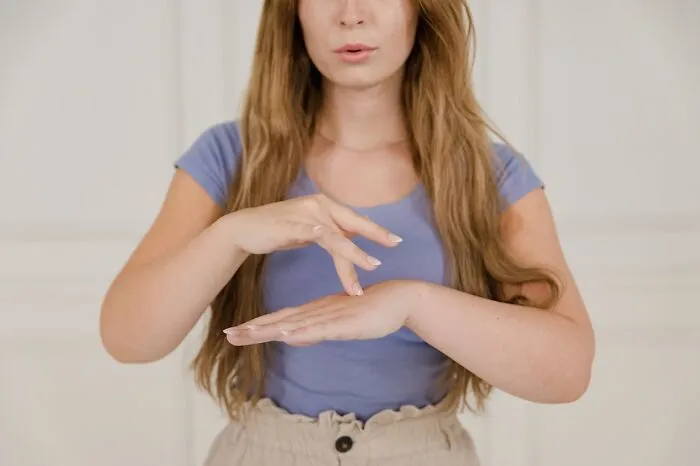 Woman in a purple shirt showing a stop gesture with her hands to shut down men’s creepy advances confidently.